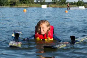 junges Mädchen mit Wakeboard im Wasser beim Schwimmen an Land in Süsel Seeparx