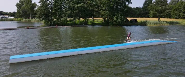 Wakeboarderin fährt vorbei an einem Hindernis im Wasser im Süsel Wakeboard Park