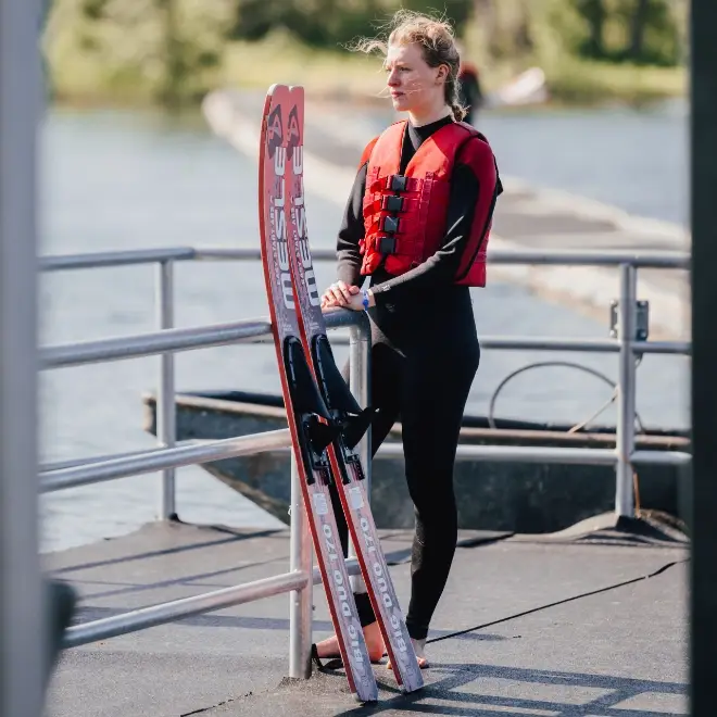 Junge Frau mit Wasserskiern schaut über den See in Süsel Seeparx