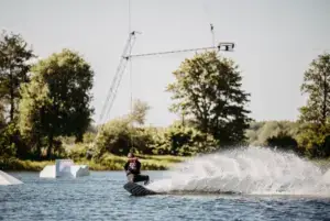 Wakeboarder beim Fahren mit spritzendem Wasser in Süsel Seeparx