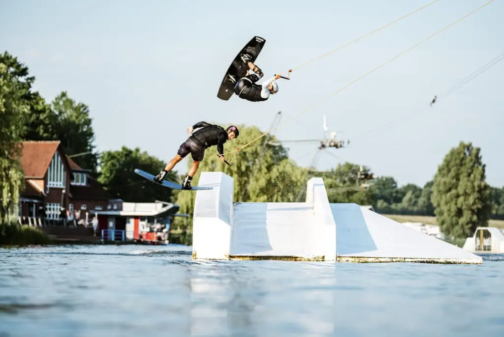 Zwei Wakeboarder im Sprung über ein Hindernis im Wakeboard Park in Süsel