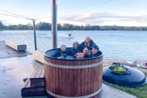 Wassersportler in Neoprenanzügen im Fass in warmem Wasser am Ufer der Sees in Süsel im Wakeboard Park